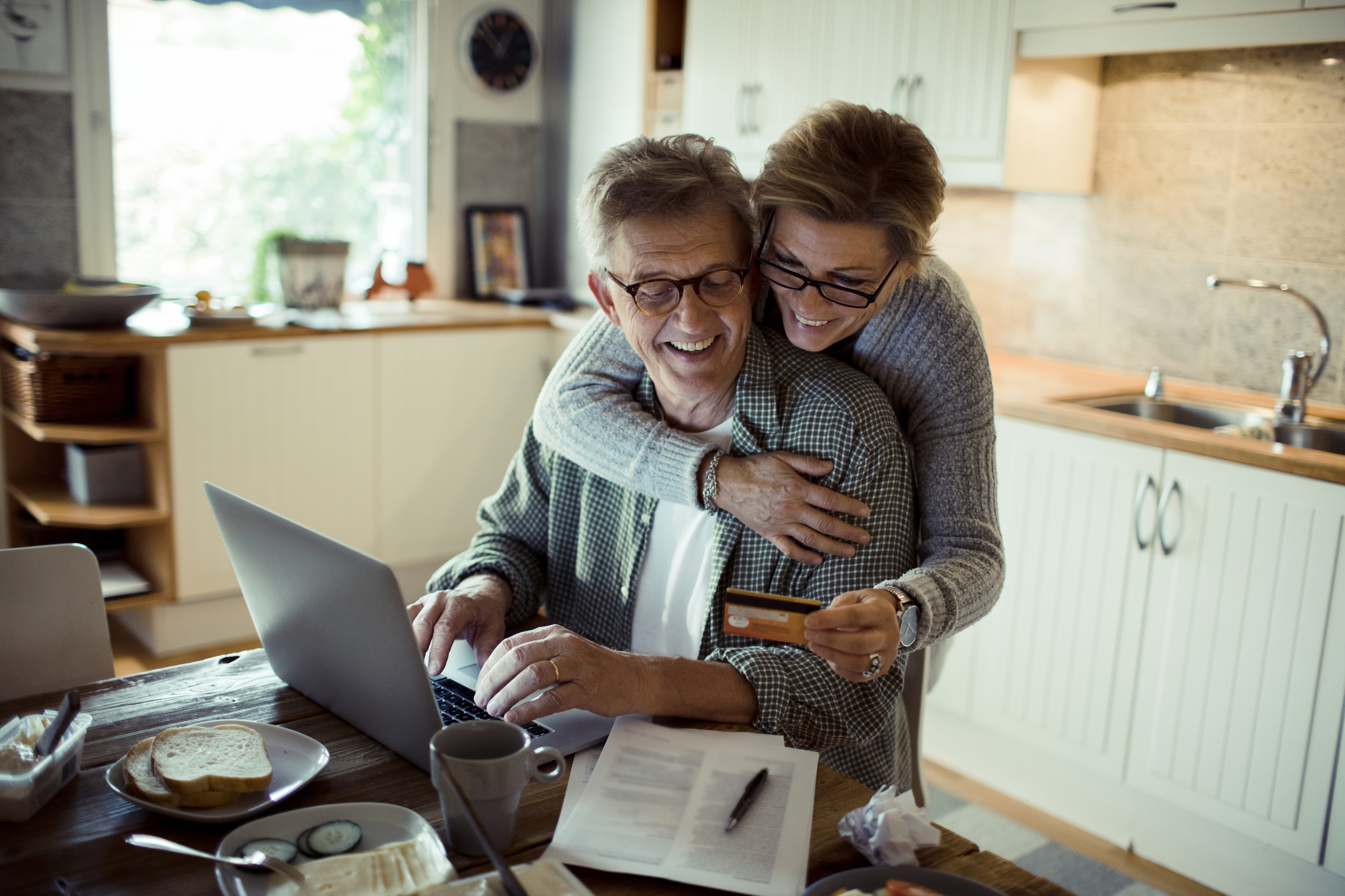 Smilende ægtepar der aflæser deres kreditkort ved computeren