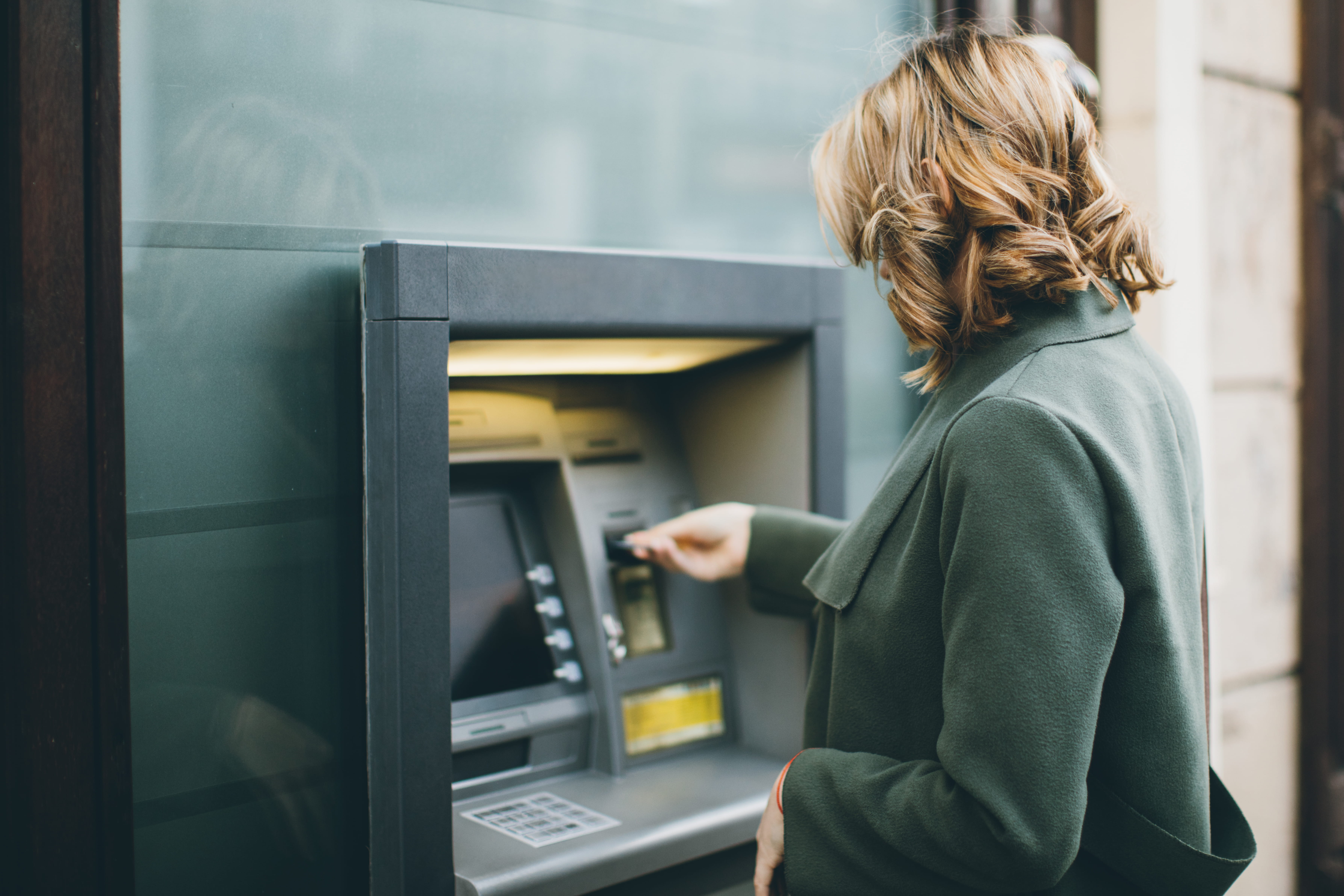 Kvinde der stikker sit kort i en bankautomat 