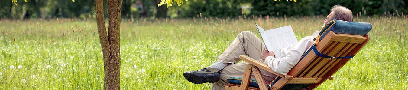 Ældre mand der slapper af i sin havestol med en bog