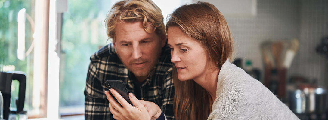 mand og kvinde kigger på mobilen