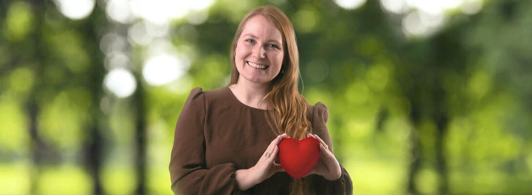 Ung kvinde holder et rødt hjerte i hænderne